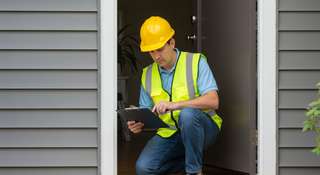 Professional in reflective vest and helmet managing a home inspection.