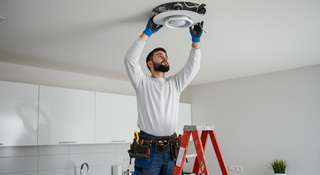 Técnico realizando trabajos de electricidad en el techo durante el mantenimiento de una vivienda